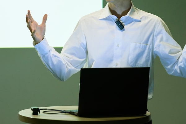 Foto de un hombre que realiza una presentación con un micrófono en la ropa