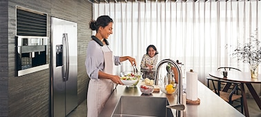 Mujer en la cocina preparando comida mientras escucha música con un parlante portátil SRS-NS7