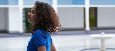 Imagen de ejemplo de una mujer caminando por un pasillo luminoso en el patio, mirando hacia el centro del patio