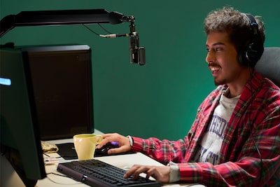 Imagen de uso de un hombre con audífonos conectados por cable a un micrófono, sentado frente a la pantalla de una PC