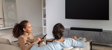 Familia disfrutando de la música en la sala de estar con un televisor con una barra de sonido HT-A5000 en un gabinete de mármol